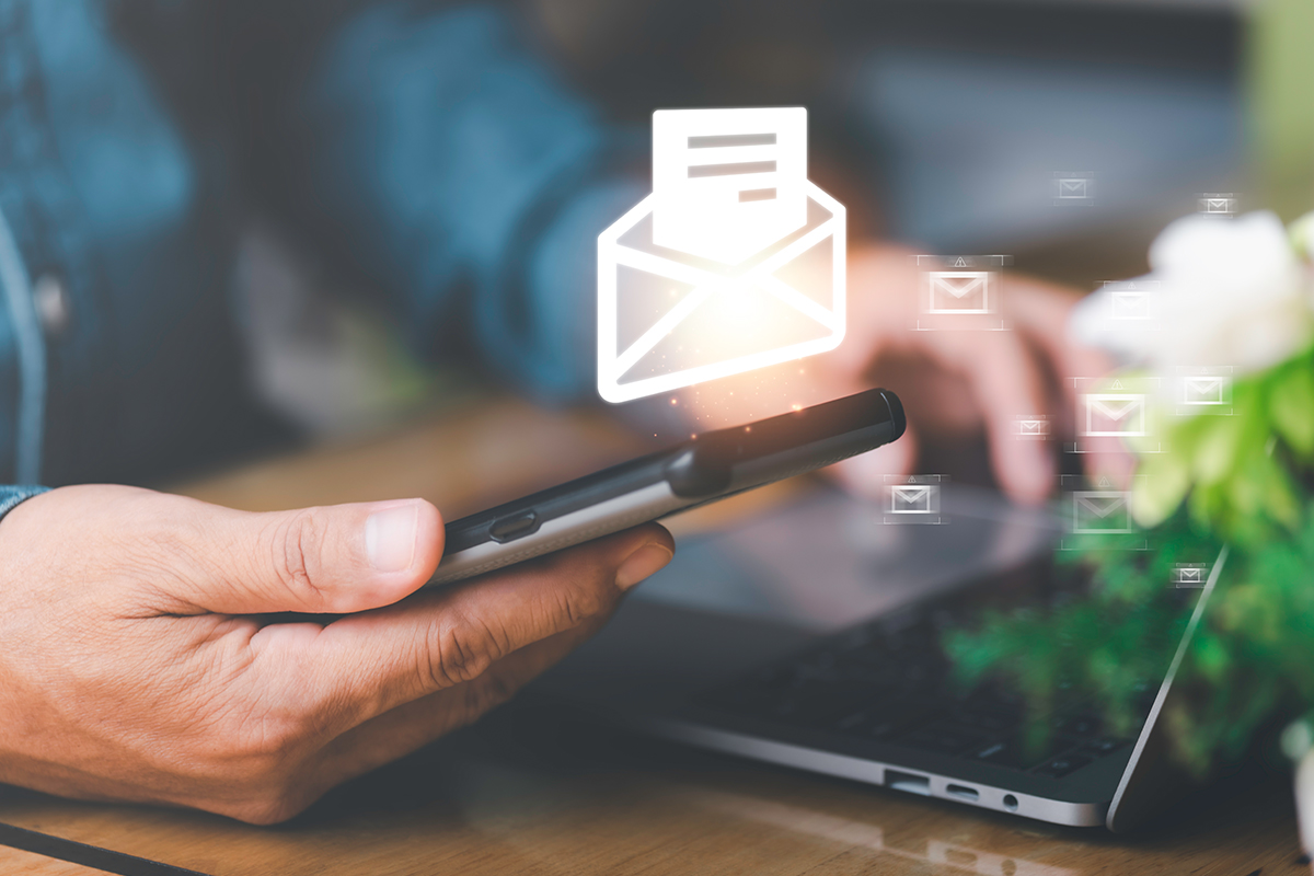 Person using a smartphone to read emails with digital email icons displayed above the device