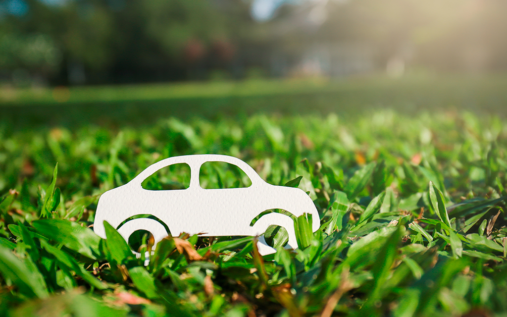 Paper car on grass with a sunny background