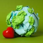 Representation of the Earth made of blue and green paper, with a red heart beside it on a green background.