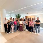 A group of people posing formally indoors. A sunny scene with summery clothing.